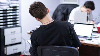 a-man-sitting-at-a-desk-in-front-of-a-laptop-computer.jpg a man sitting at a desk in front of a laptop computer